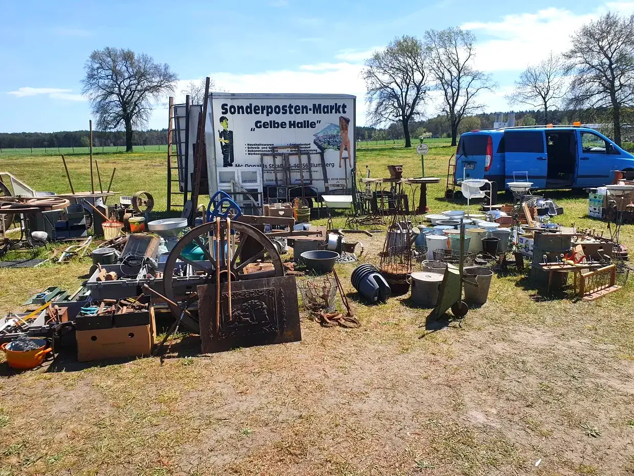 Trödelmarkt auf dem Hofgelände mit Ständen voller Werkzeug, Kannen und Fundstücken
