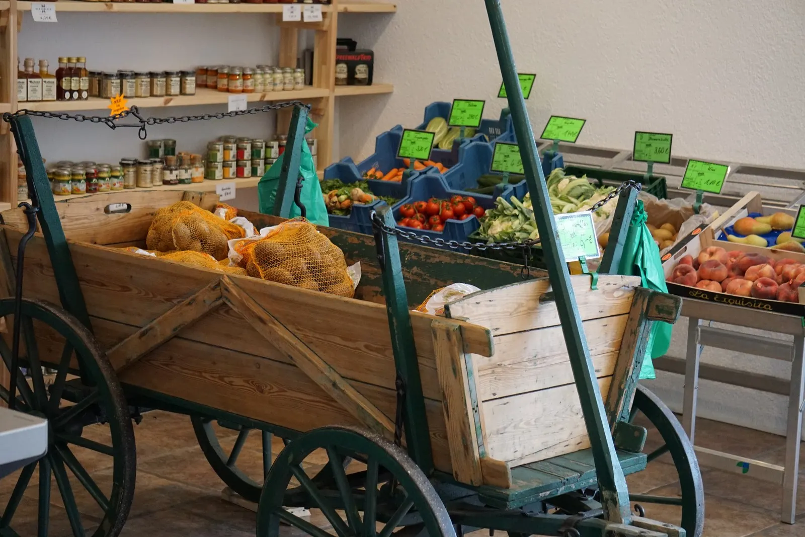 Alter Leiterwagen mit Kartoffeln und Gemüse vor den Regalen im Hofladen Luckau