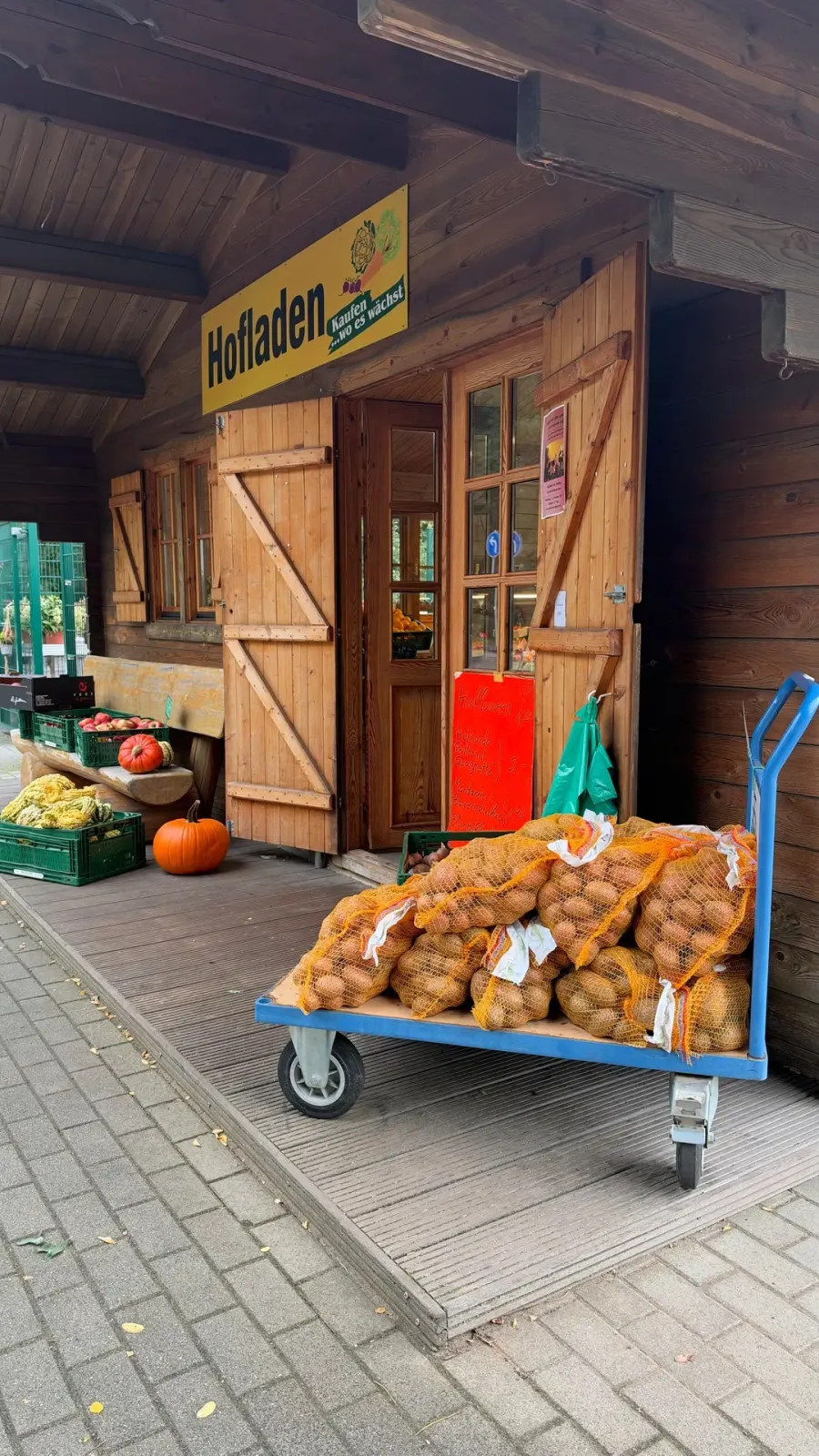 Eingang des Hofladens Lübben mit Kartoffelsäcken auf dem Handwagen