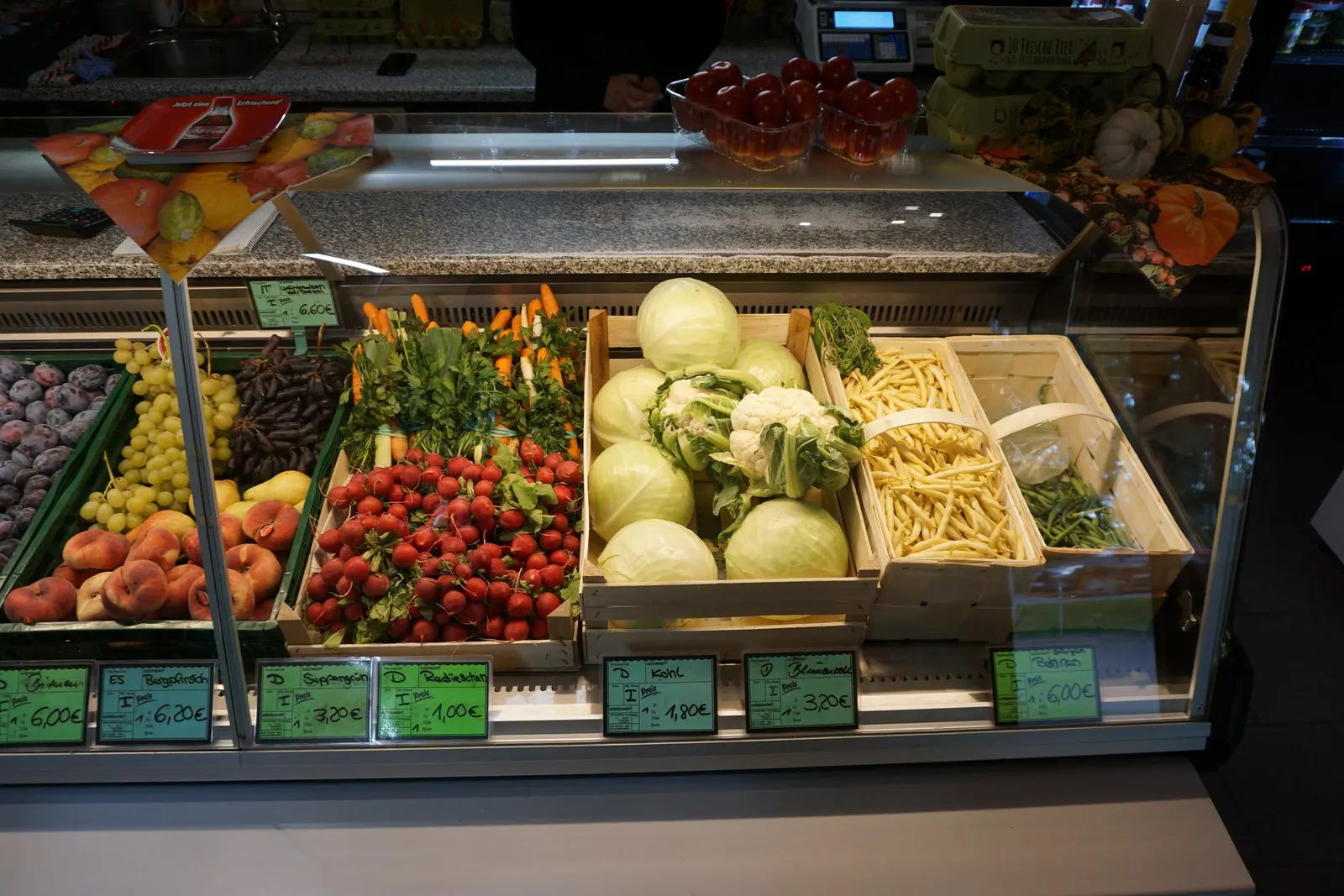 Kühltheke mit Erdbeeren, Pflaumen, Blumenkohl und Bohnen