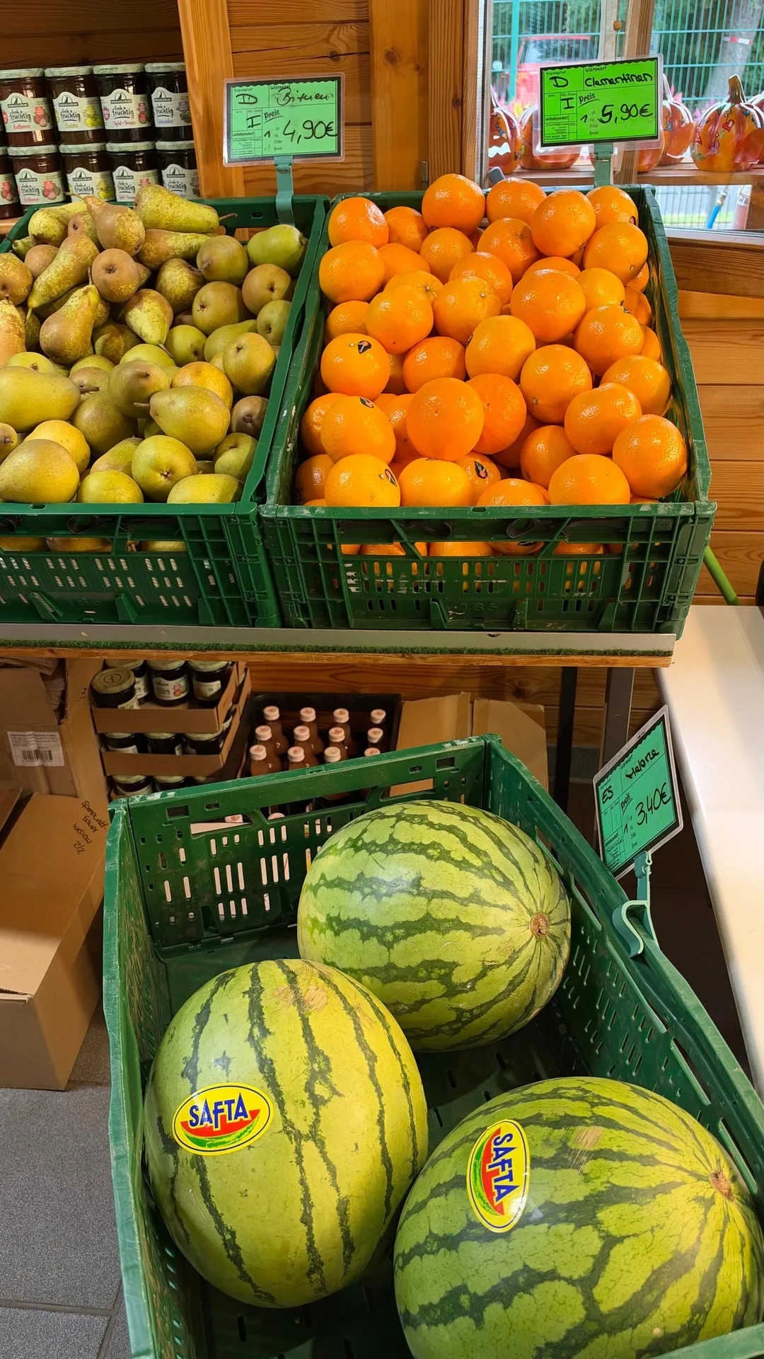 Birnen, Orangen und Wassermelonen in grünen Kisten im Hofladen