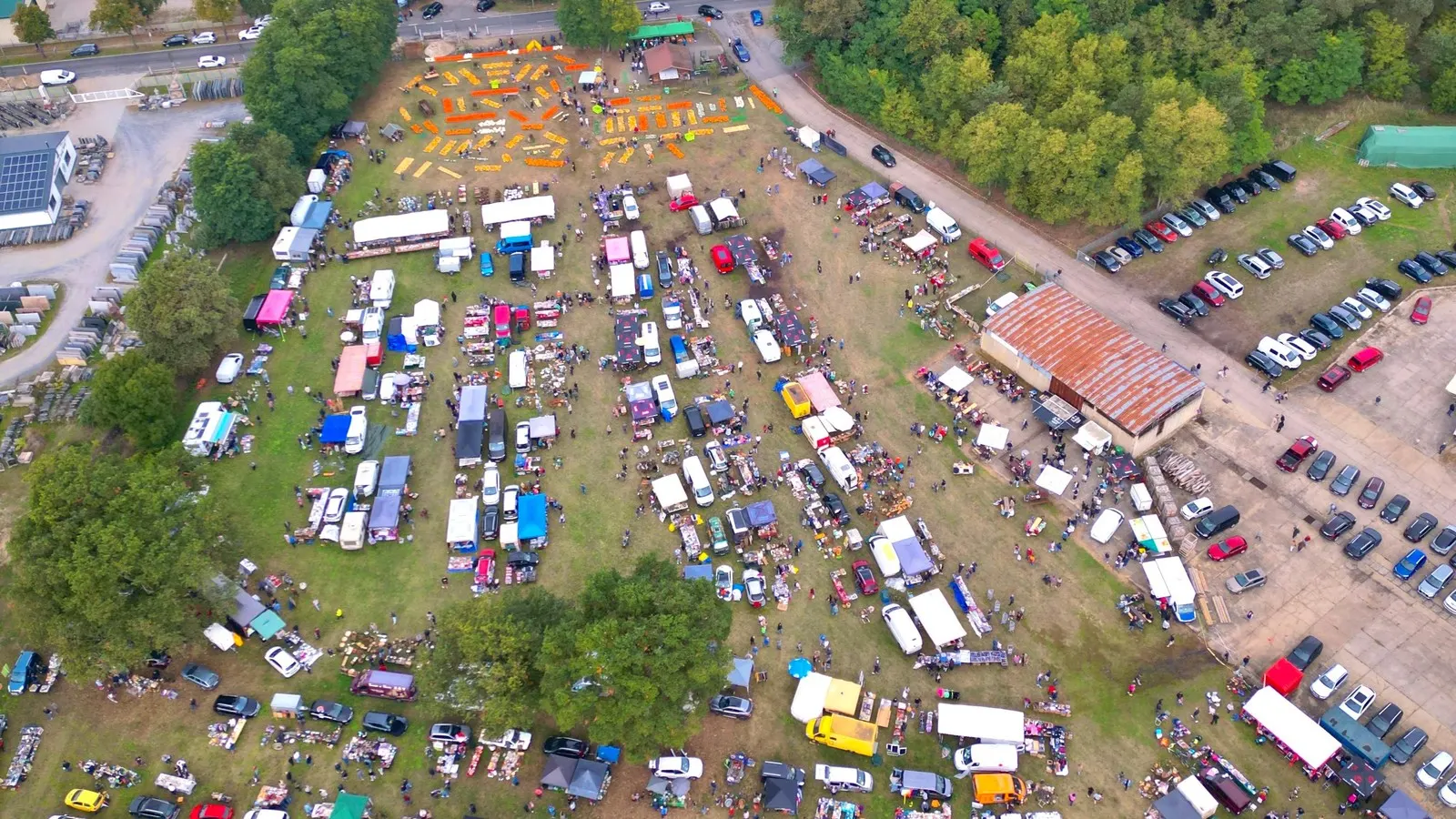Der Trödelmarkt 2026 auf der Kürbiswiese Lübben von oben: lange Reihen aus Ständen und Transportern, oben die Kürbisausstellung